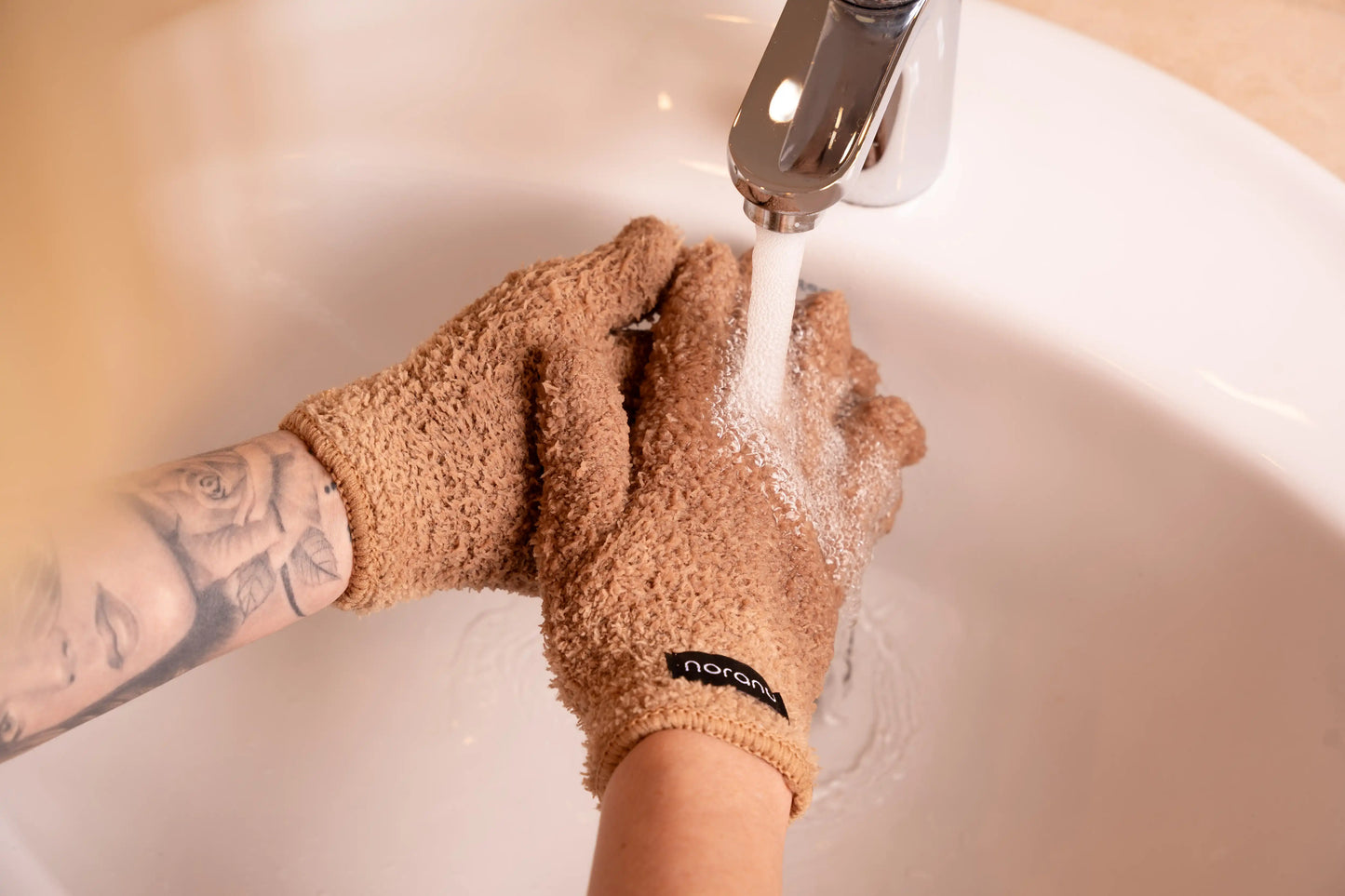 Abschminkhandschuh in Braun wird unter fließendem Wasser verwendet zur Make-up-Entfernung ohne Wattepads