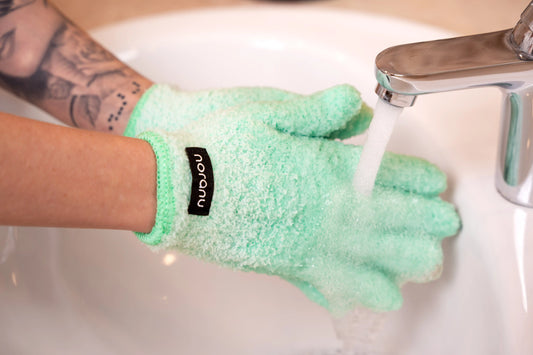 Grüner Abschminkhandschuh wird unter fließendem Wasser gereinigt zur Make-up Entfernung ohne Wattepads