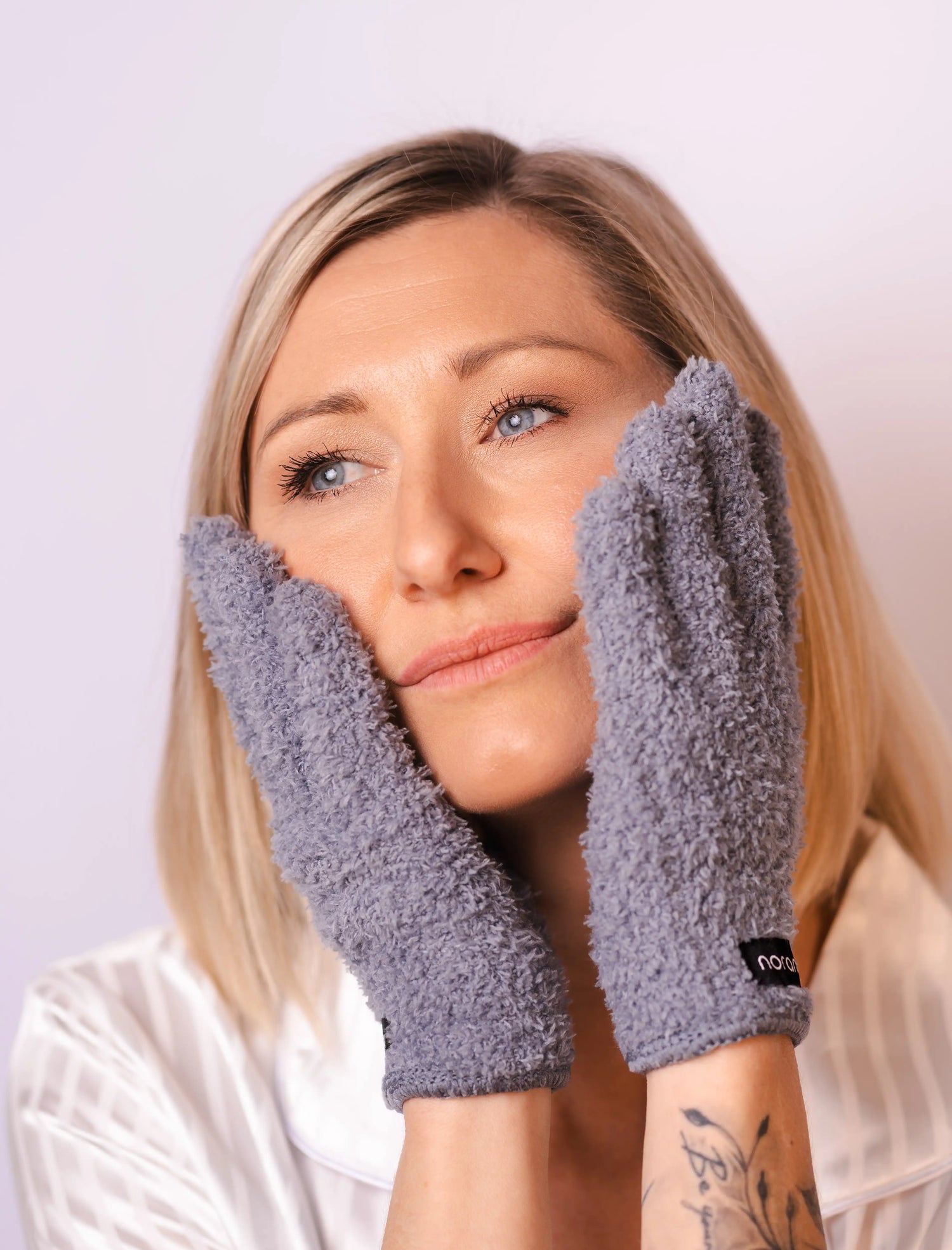 Anwendung eines Abschminkhandschuhs im Gesicht zur täglichen Make-ip Entfernung. Frau schaut glücklich und zufrieden